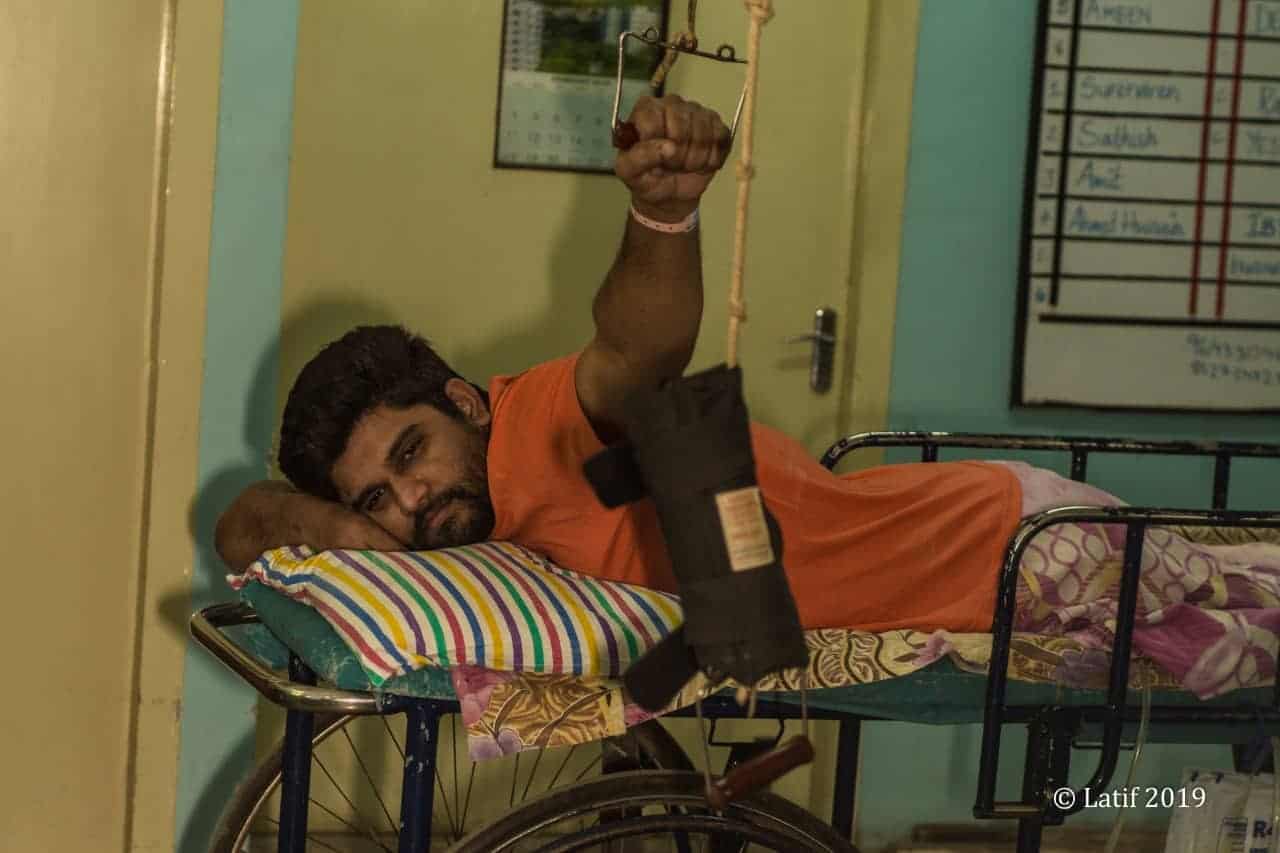 spinal cord injured man lying on his stomach on a prone trolley in rehab