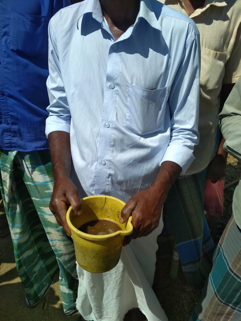 a man holds a jug filled with the home made organic manure