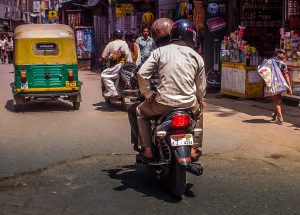Motor bike in town shows both driver and passenger with helmet