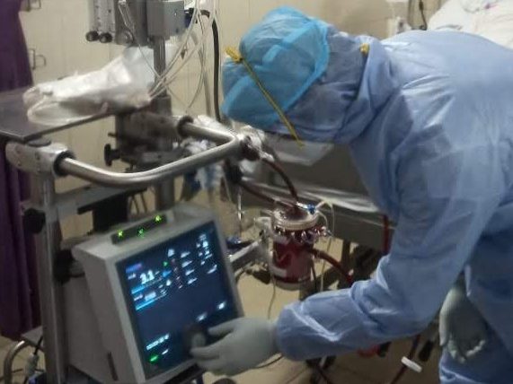 PPE equipment worn by a doctor in ICU monitoring the equipment of a patient